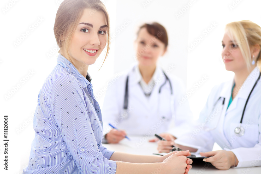 Happy smiling female patient with two cheerful doctors in the background. Medical and health care concept Happy smiling female patient with two cheerful doctors in the background. Medical and health care concept