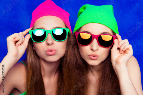 Принти на полотні Portrait of two pretty sisters in hats and glasses pouting