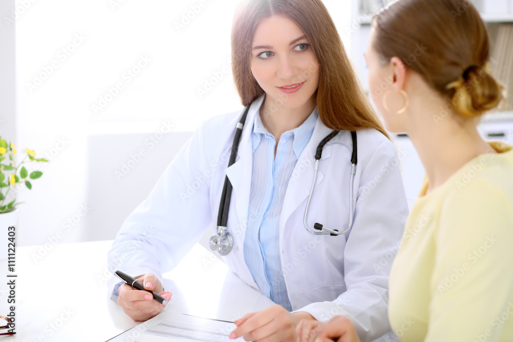 Doctor and patient sitting at the desk near window, sun shines Doctor and patient sitting at the desk near window, sun shines