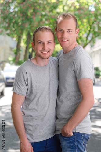 Two gays standing on a street at at sunny day  happy smiling and