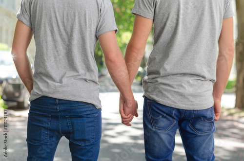 Homosexual couple outside, hold hands, back view