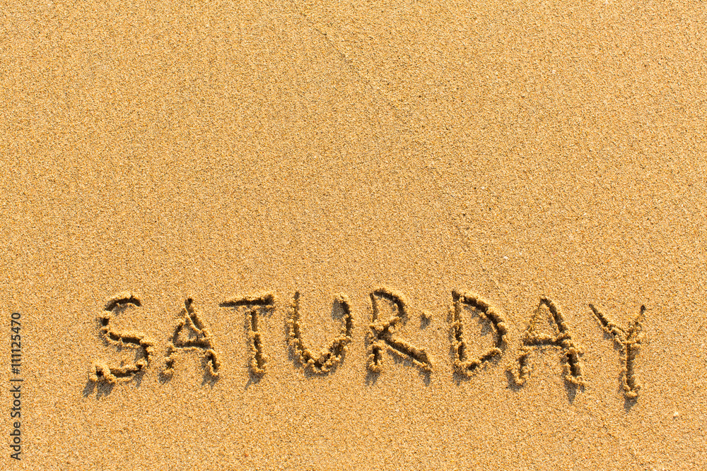 Fototapeta premium Saturday - inscription by hand on a light-golden beach sand.