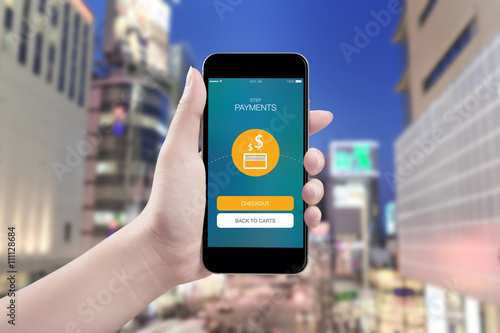 Hand holding mobile smart phone with payment screen on city background