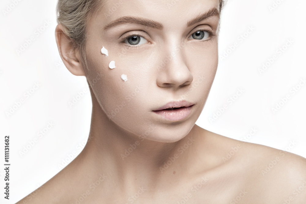 Cream and beauty. Woman with drops of cream on face