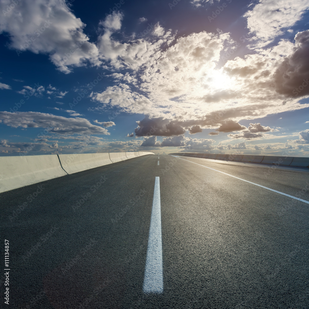 Fototapeta premium Driving on open road towards the setting sun