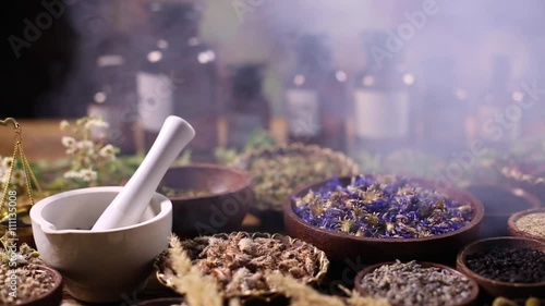 Herbs, berries and flowers with mortar, on wooden table background