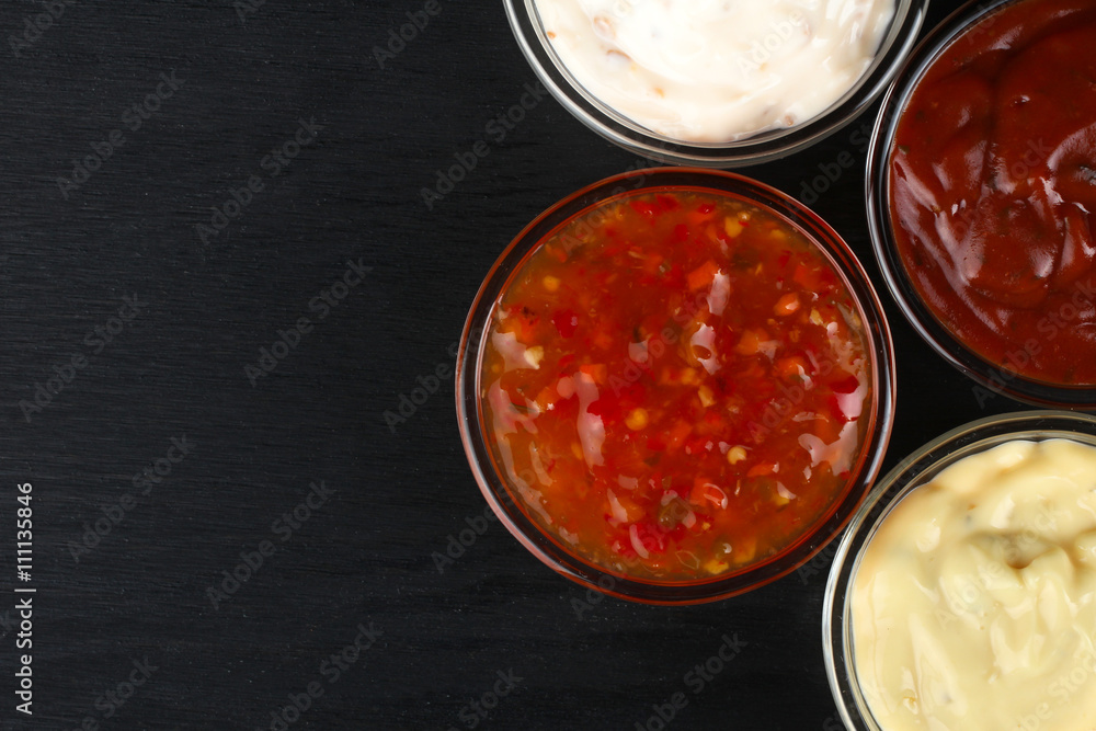 a variety of sauces in glass bowl on black wooden background a variety of sauces in glass bowl on black wooden background
