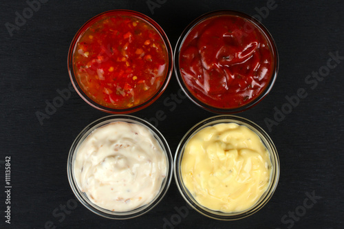 a variety of sauces in glass bowl on black wooden background