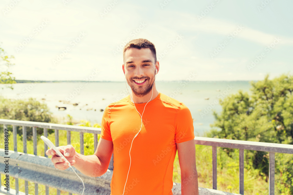 smiling young man with smartphone and earphones
