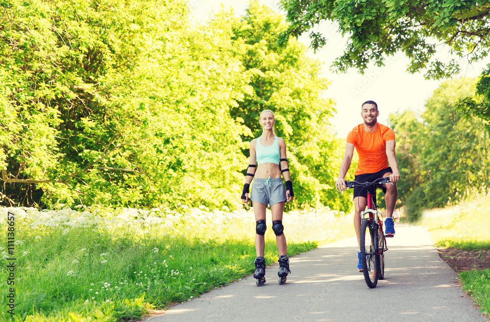 Obraz premium happy couple with rollerblades and bicycle riding