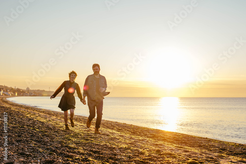 happy loving couple having fun on beach at sunset