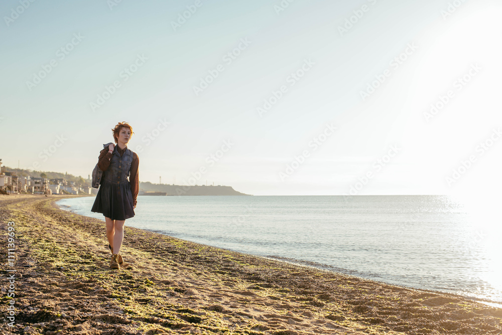 young caucasian redhead woman having fun on beach at sunset