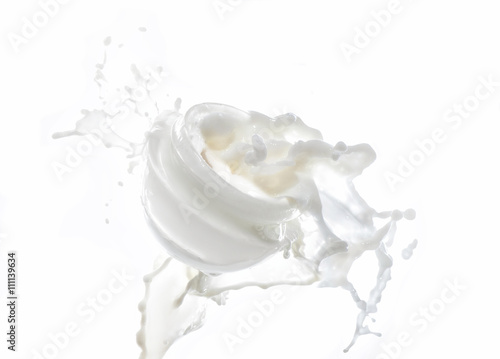Moisturizing cream, moisturizing milk in the big milk splash isolated on the white background with milk drops and splashes around the jar