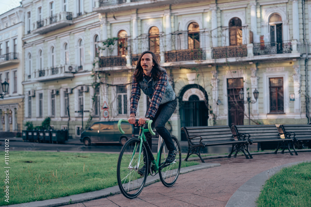 Fototapeta premium young brunette man riding fixed-gear bicycle in the city on a sunny day