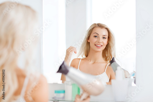 happy young woman with fan drying hair at bathroom