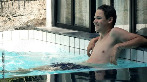 Happy, teenage boy relaxing in swimming pool, super slow motion 240fps

