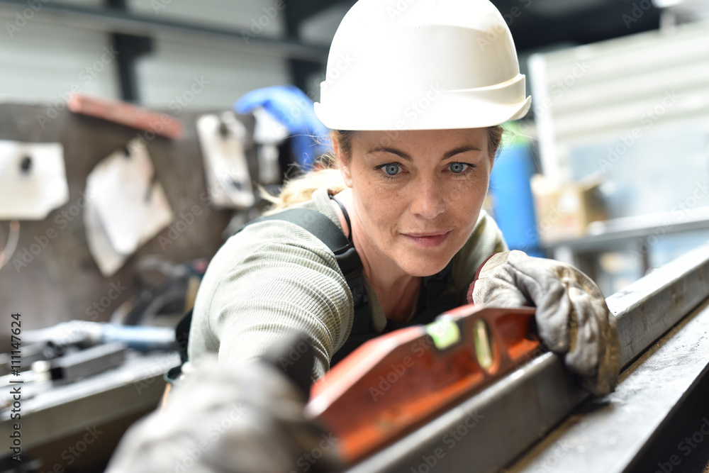 Metalworker with hardhat working on machine Metalworker with hardhat working on machine