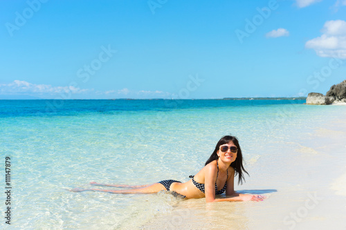 Young happy woman in black bikini enjoys sunny day on beach. Tropical vacation