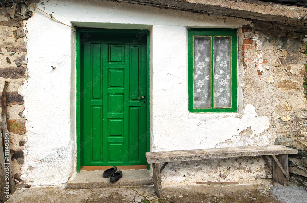 Old house wall with wooden door, window and bench