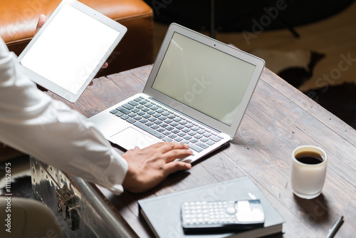 Businessman working at office desk and signing a document, computers and paperwork all around, top view



