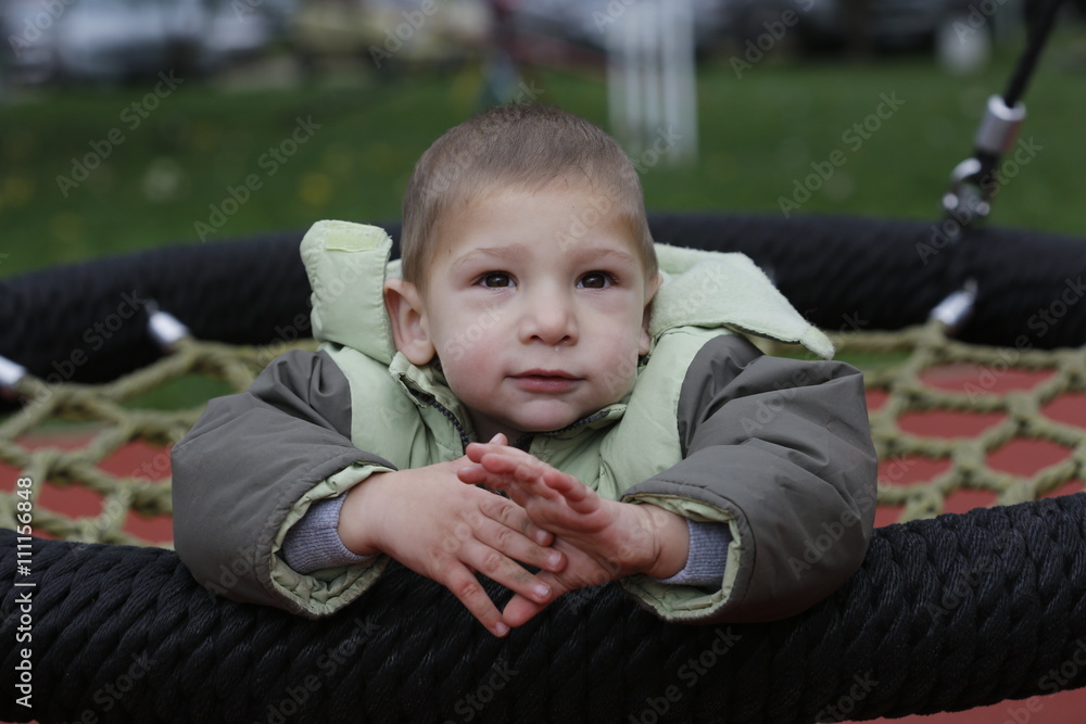 Little child in autumn jackets swinging in a swing Little child in autumn jackets swinging in a swing