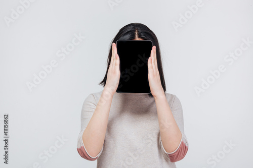 Schilderij op canvas Pretty brunette girl cover her face with tablet computer