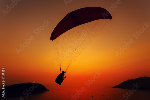 Paraglider silhouette against the background of the sunset sky