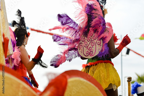 Back view photo of carnaval queen at carnival parade with colorful feathers. 