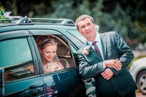 bride and groom near the car. Bride in the car smiling