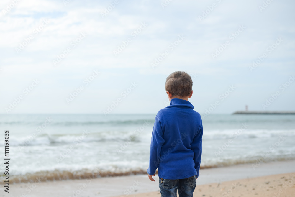 Back view portrait of cute boy at the beach on ocean background