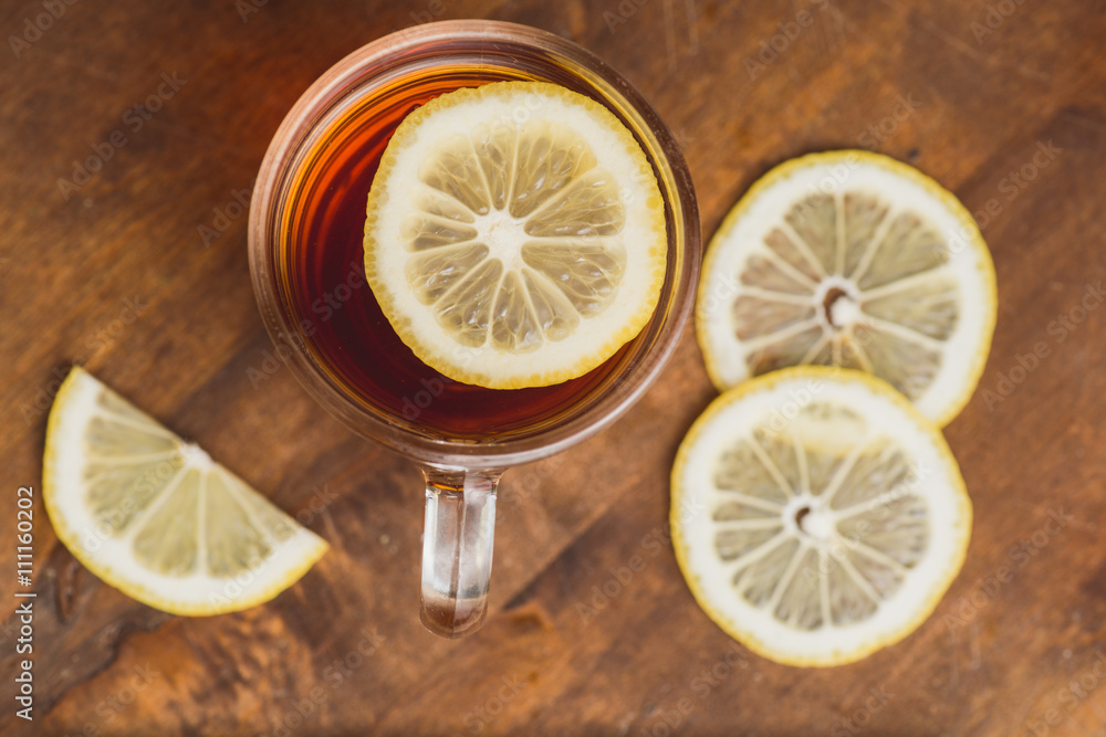 Top view of black tea with lemon in cup and on wooden plank table Top view of black tea with lemon in cup and on wooden plank table