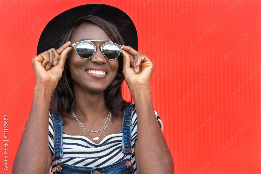 Beautiful smiling african woman in a black hat over colorful red