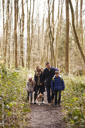 Family with pet dog walking in a wood, vertical © Monkey Business