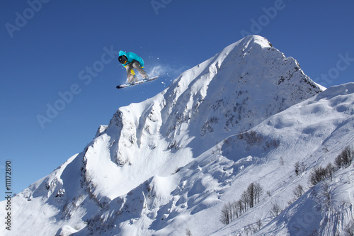 Snowboard rider jumping on winter mountains. Extreme snowboard freeride sport.