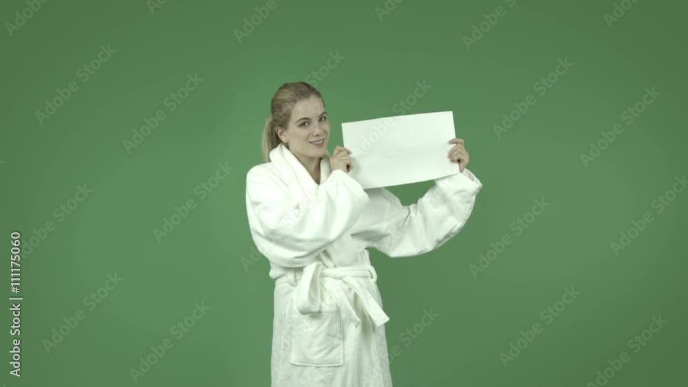 attractive caucasian girl in bathrobe isolated on green smiling with blank sign attractive caucasian girl in bathrobe isolated on green smiling with blank sign