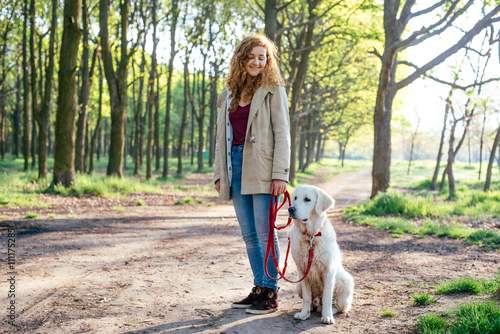 beautiful young girl walking with labrador dog in park 