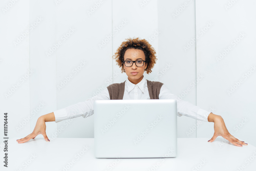 Serious african american businesswoman sitting and posing with laptop Serious african american businesswoman sitting and posing with laptop