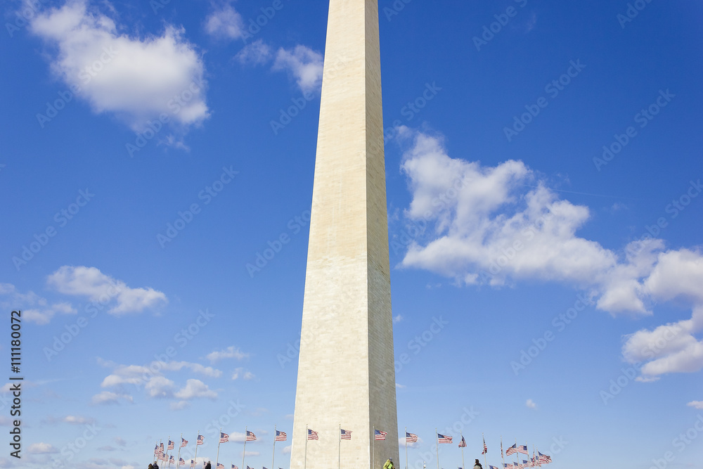 Obraz premium Gleaming white stone & two-tone stonework of America's national monument, the Washington Monument with fifty American flagpoles circling the plaza below, The Mall, Washington DC