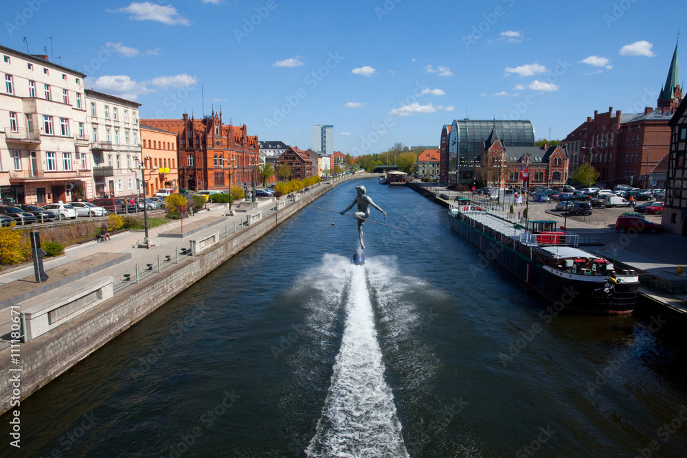 Obraz premium Widok z mostu na rzeźbę zawieszoną na linie i bulwar nad Brdą, Bydgoszcz, Polska