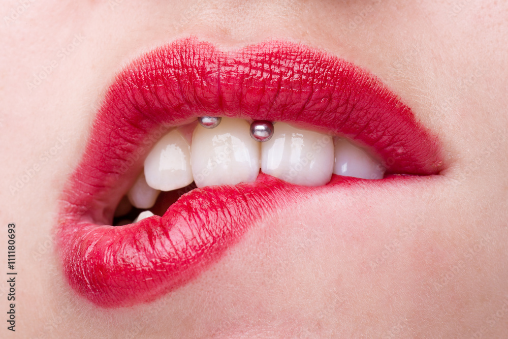 Fototapeta premium Kobieta z Smiley piercing gryzie jej usta czerwoną szminką