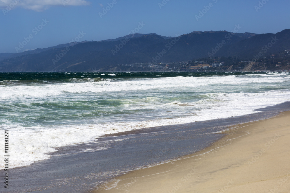 The waves of the Pacific ocean, the beach landscape. The ocean, mountains and blue sky in USA, Santa Monica. 
