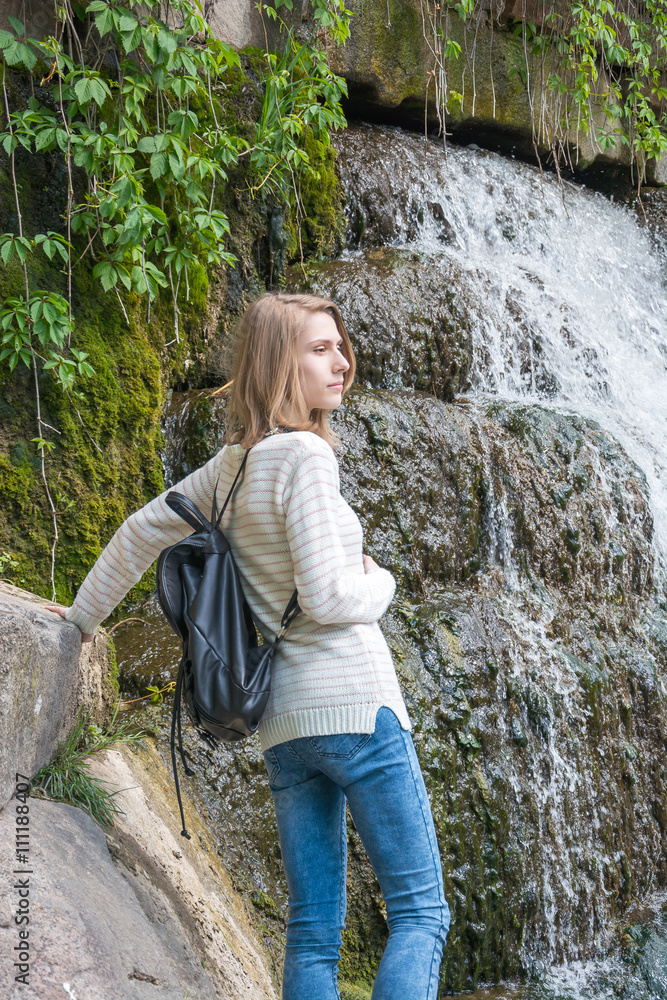 Girl standing near a waterfall in a park Girl standing near a waterfall in a park