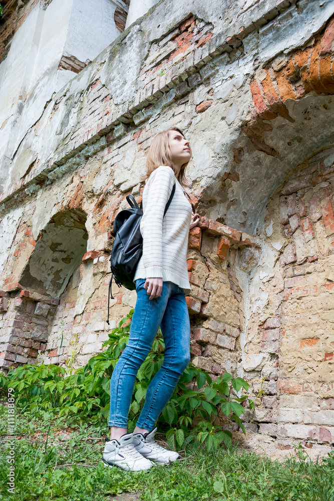 Girl standing near the destroyed wall in a park