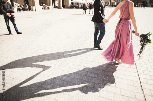 wedding. beautiful couple, bride with pink dress walking in the old city Krakow, their shadows