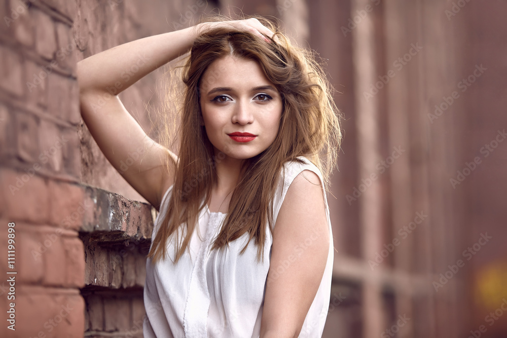 Fototapeta premium young woman near a brick wall. Fashion concept. City lifestyle. Female fashion. Closeup portrait 