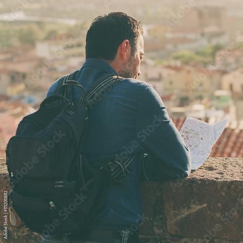 Handsome tourist man looking at map in amazing italian city
