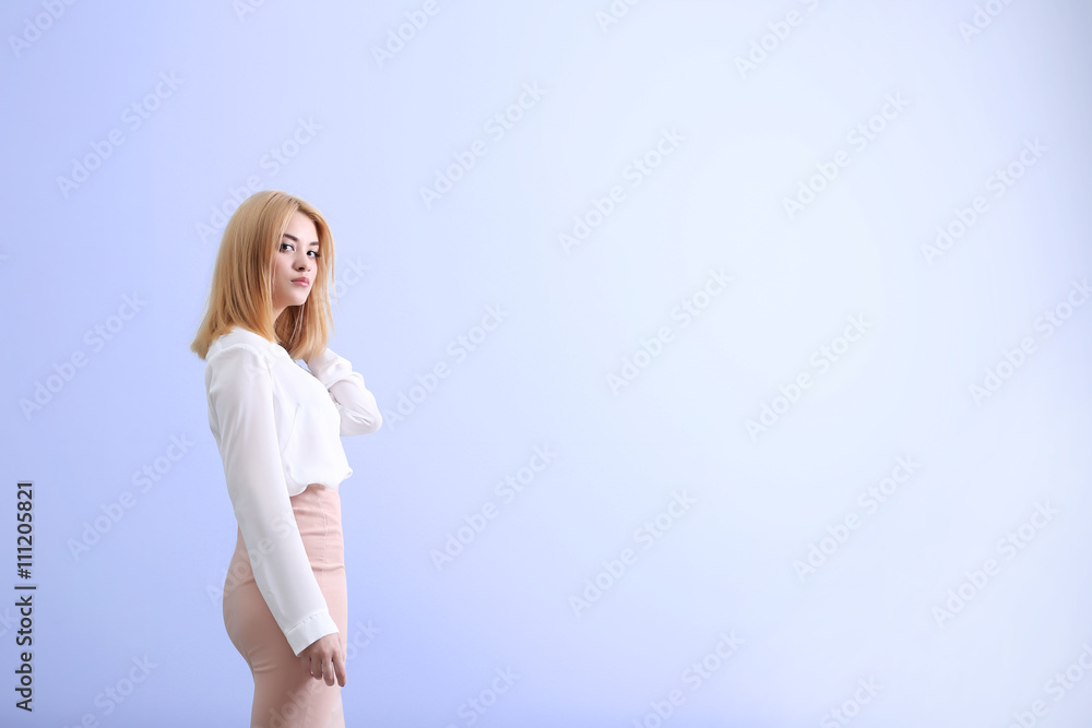 Beautiful blonde young woman in white shirt and pink skirt on blue wall background Beautiful blonde young woman in white shirt and pink skirt on blue wall background