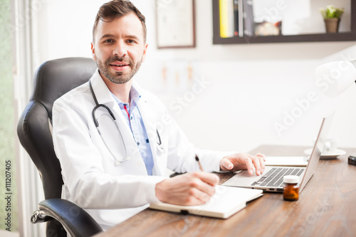 Friendly young doctor working in his office