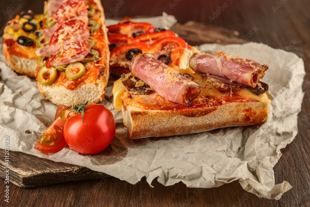Hot pizza baguette with bacon and cheese on wooden table