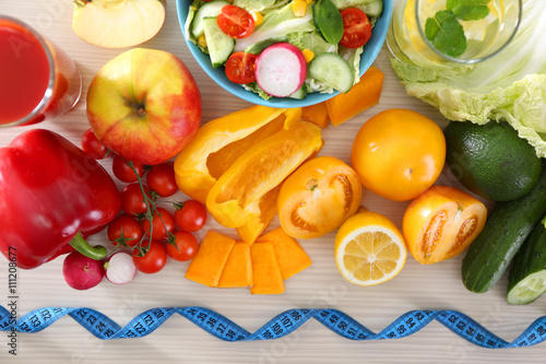 Fresh fruits and vegetables with measuring tape on wooden table, top view